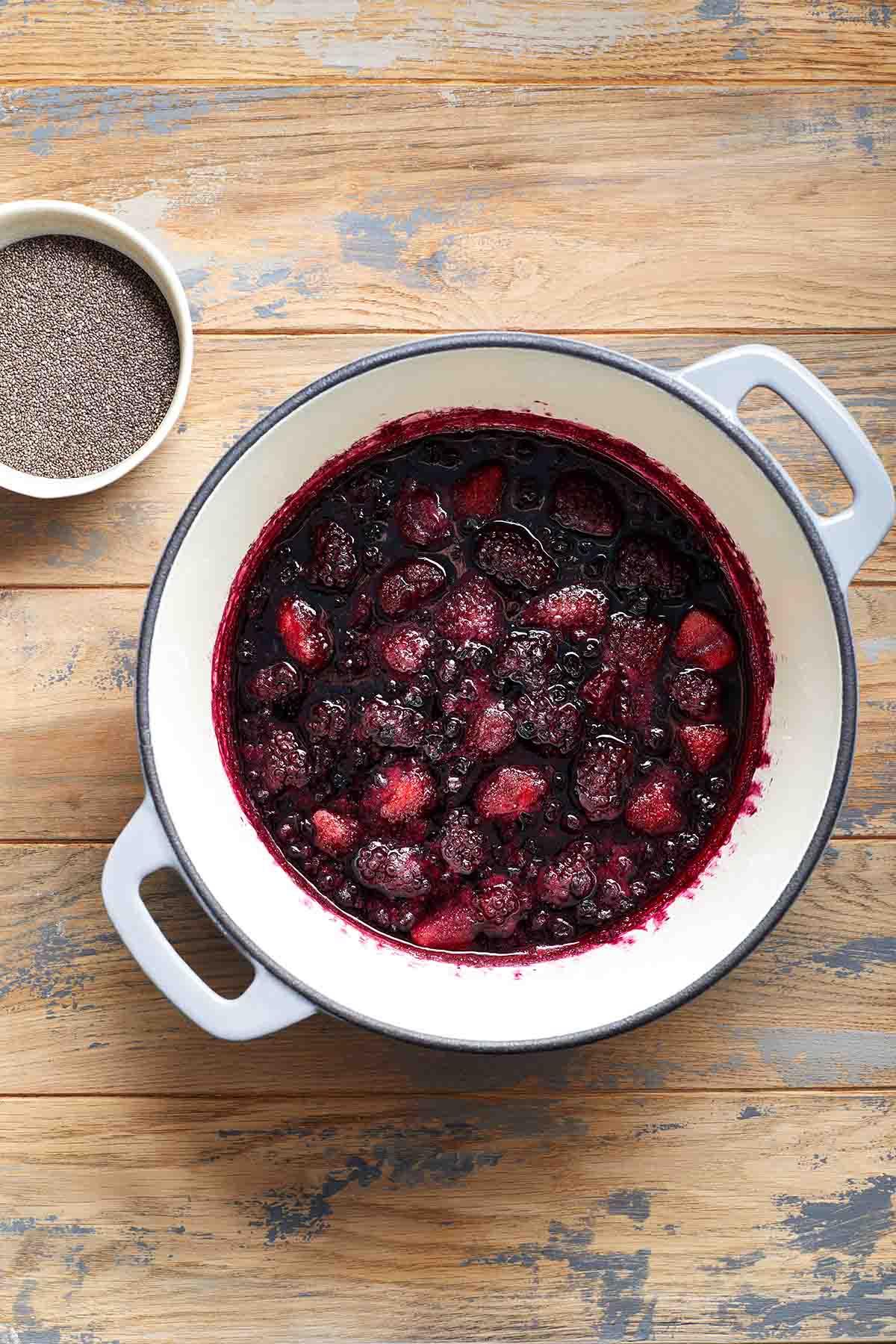 Berries cooked down in a pot with chia seeds on the side.