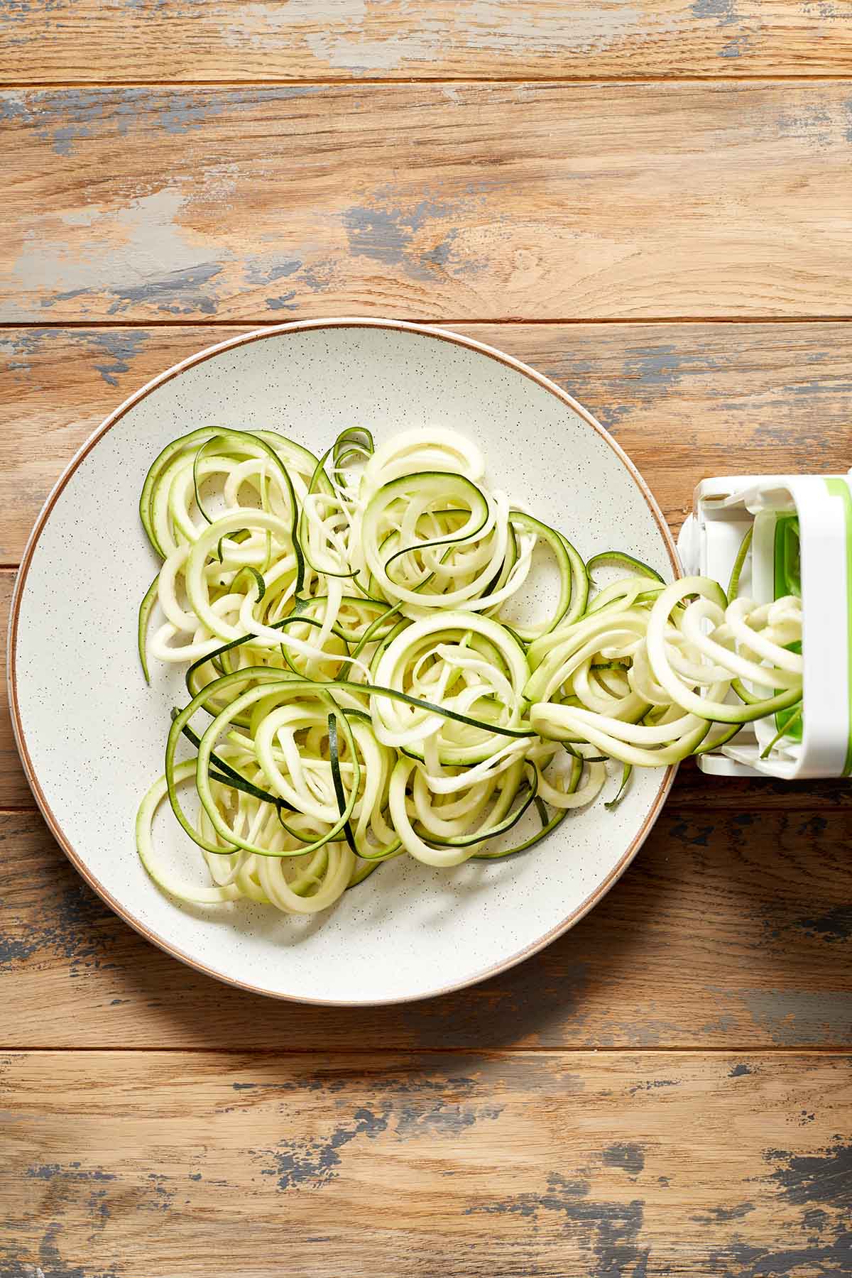 Overhead view of spiralized zucchini noodles on a white plate.
