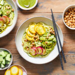 Overhead view of zucchini noodle bowls arranged on a wooden table.