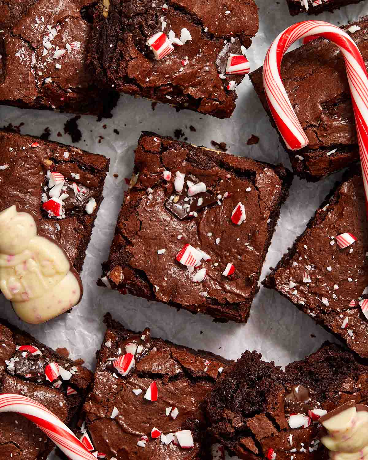 Brownies arranged on parchment paper with candy canes and peppermint bark.