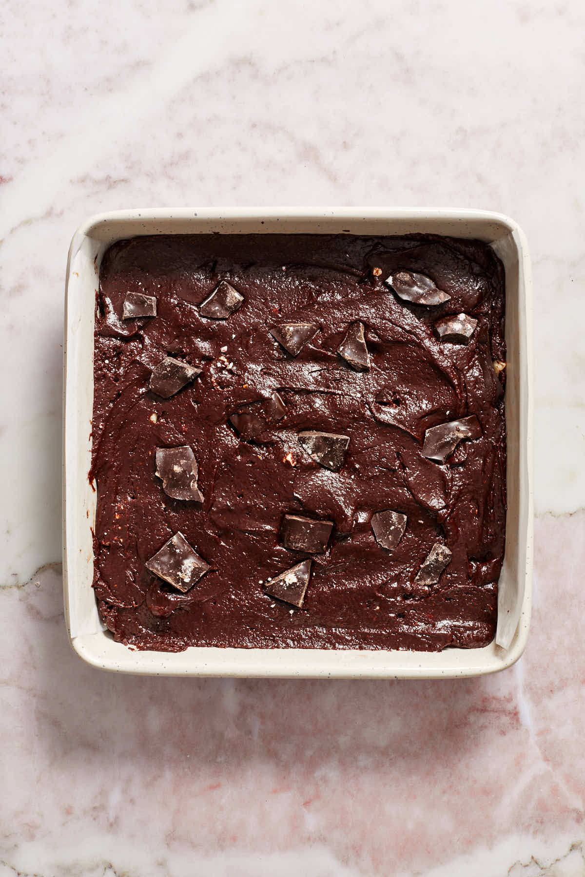 Brownie batter spread out in prepared pan with peppermint bark pressed into the top.