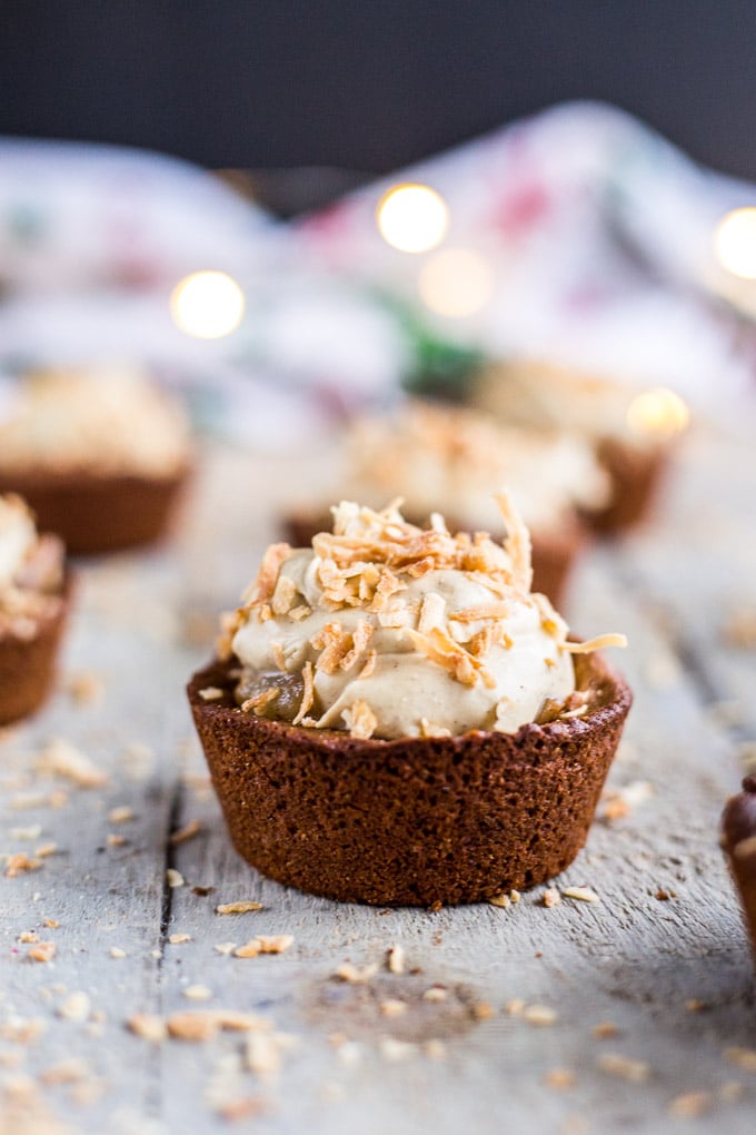 Side view of a gingerbread cookie cup topped with pears and coconut whipped cream.