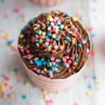 Close up overhead of chocolate flourless ricotta cupcake with sprinkles on top.