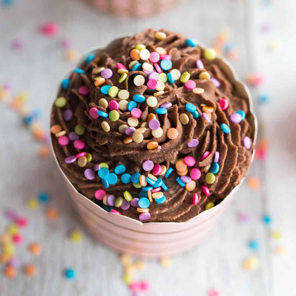 Close up overhead of chocolate flourless ricotta cupcake with sprinkles on top.