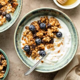 Peanut butter granola in a green bowl with yogurt and blueberries.