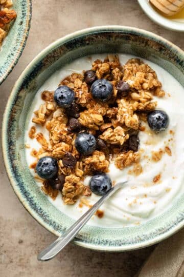 Peanut butter granola in a green bowl with yogurt and blueberries.