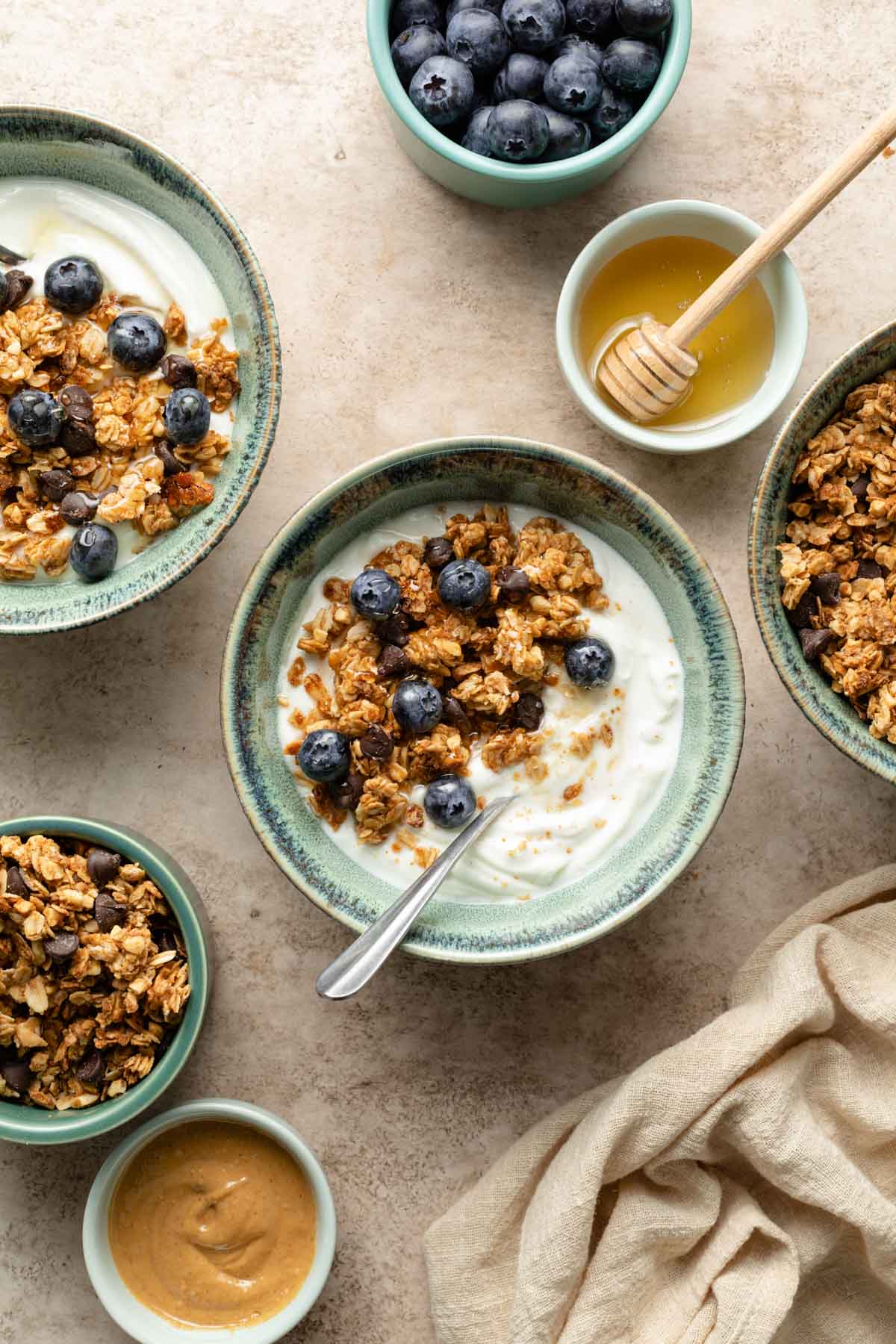Overhead view of yogurt in green bowls and topped with peanut butter granola and blueberries.