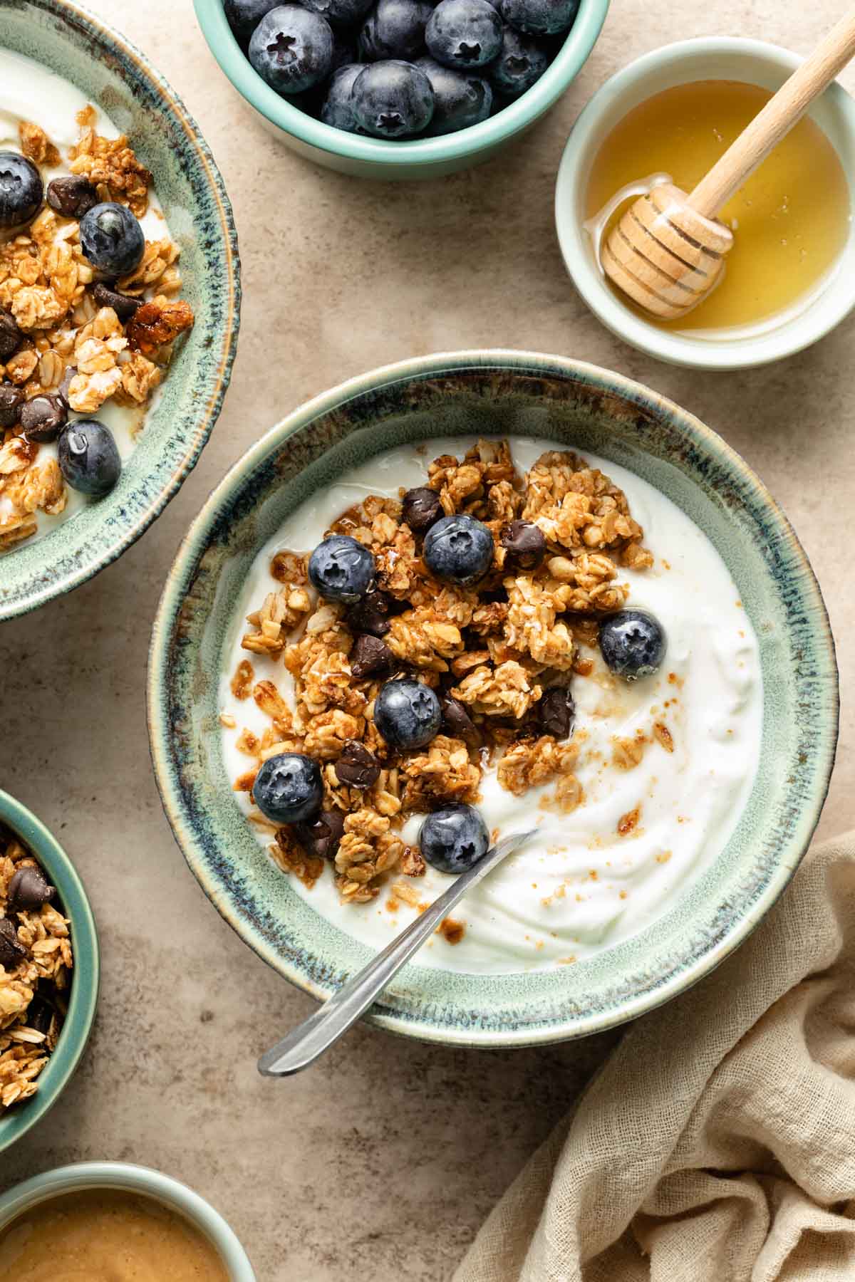 A bowl of yogurt with granola, honey and blueberries on top. 