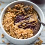 Overhead of chocolate peanut butter chia pudding in a small white bowl with a spoon.