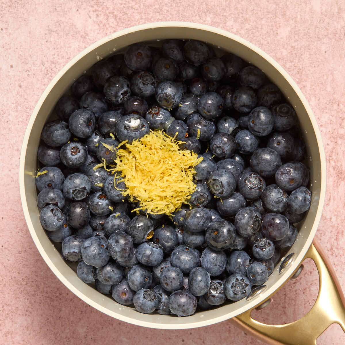 Blueberries in a small sauce pan with lemon zest on top.