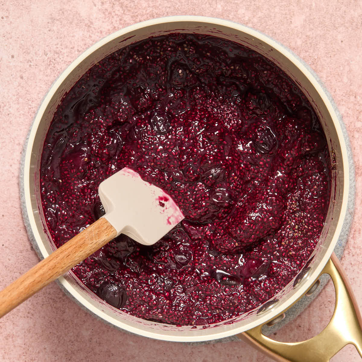 Chia jam thickened in a sauce pan with a spatula inserted into it.