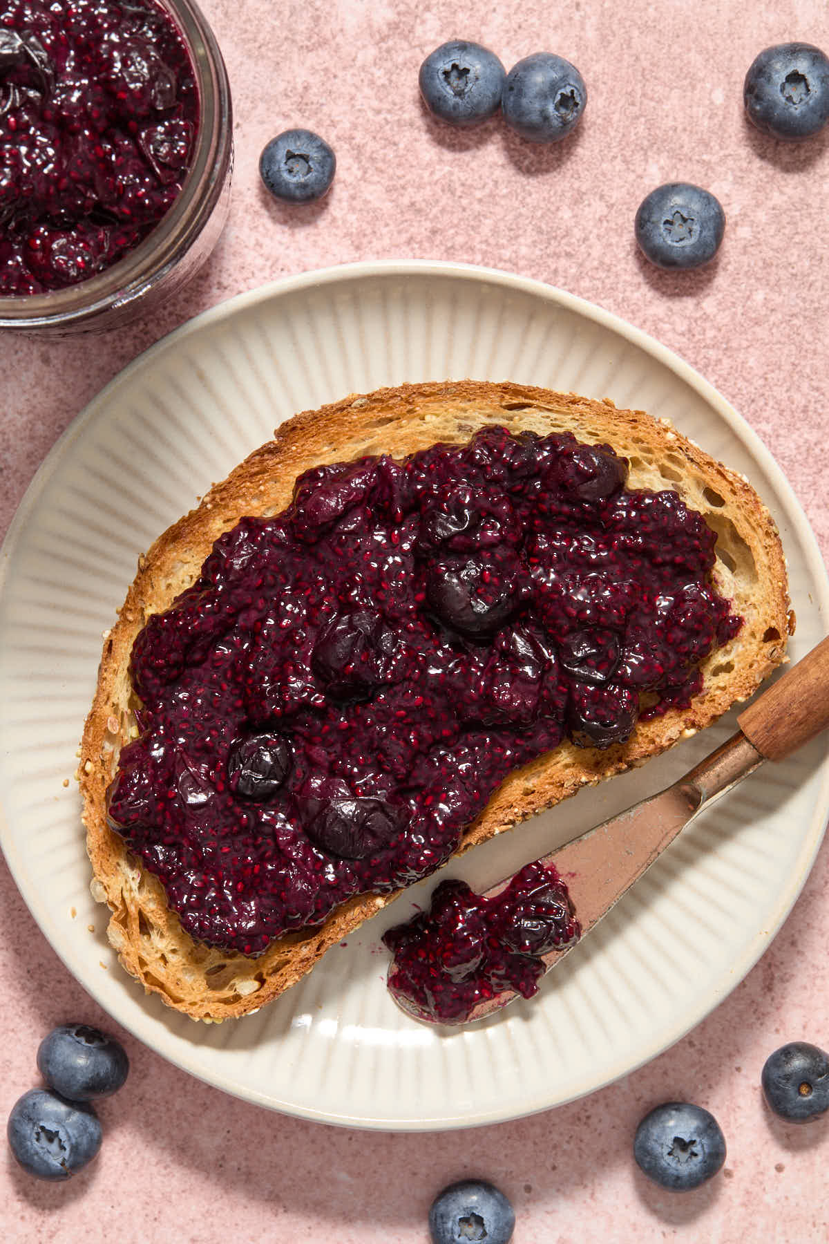 Slice of toast on a plate with jam spread over top.