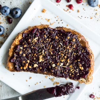 Overhead view of Blueberry Pomegranate Chia Jam on a slice of toast that's on a white plate.