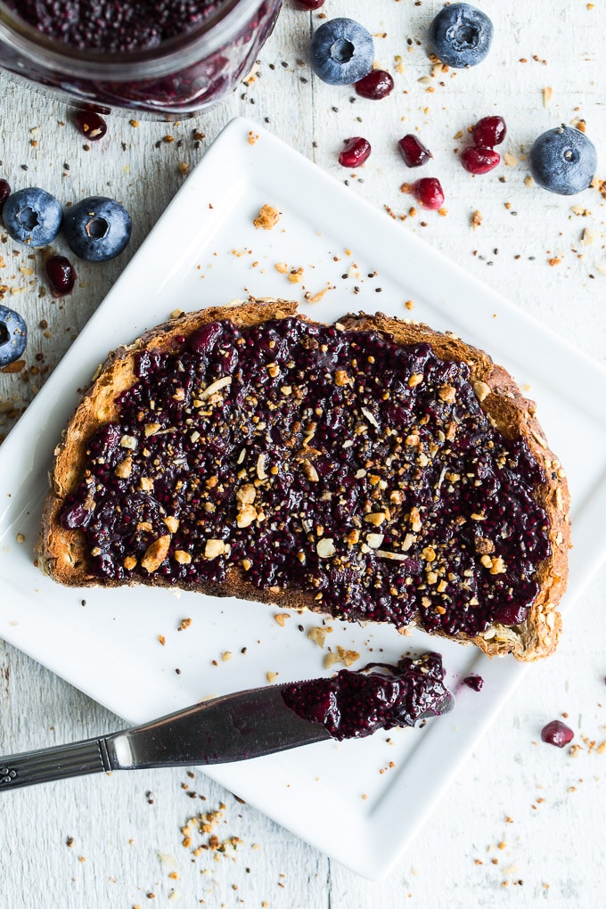 Overhead view of Blueberry Pomegranate Chia Jam on a slice of toast that's on a white plate.