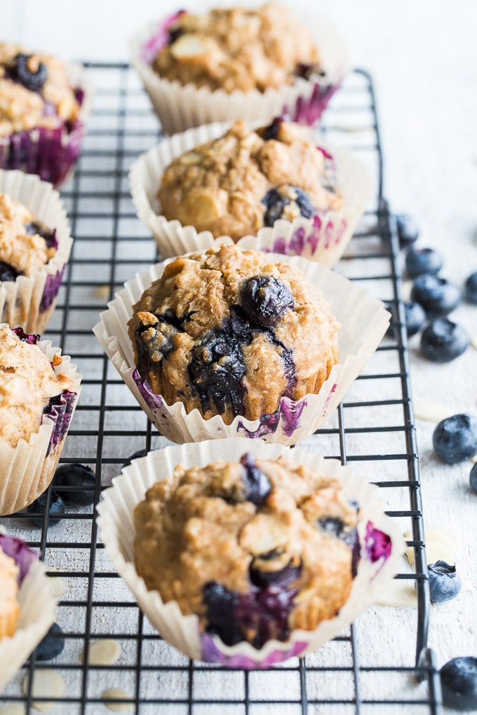 Older photo of blueberry muffins in cupcake liners on a wire rack.