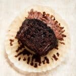 Close up view of a chocolate zucchini cupcake with a bite taken out of it.
