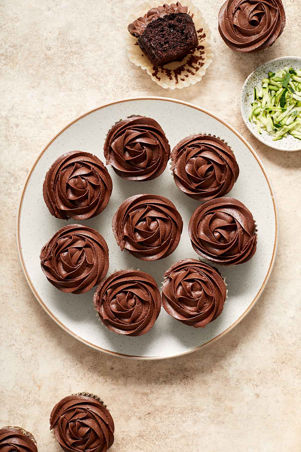 Overhead view of zucchini cupcakes on a plate and topped with chocolate frosting.