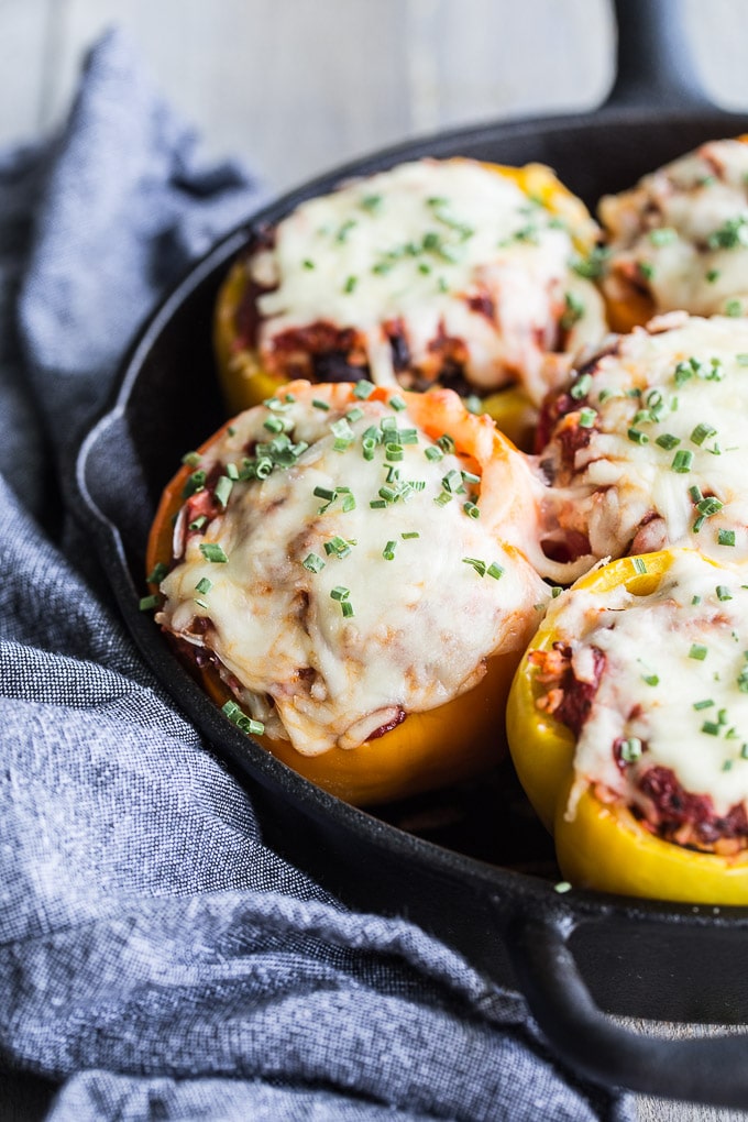 Up close view of Vegetarian Stuffed Peppers in a black cast iron pan next to a blue napkin.