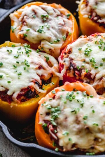 Close up view of stuffed vegetarian peppers in a cast iron skillet.