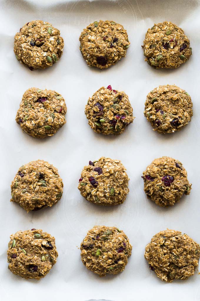 Overhead view of Avocado Pumpkin Oatmeal Breakfast Cookies arranged on a baking sheet lined with parchment paper.
