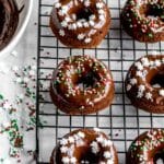Overhead of mini gingerbread donuts topped with sprinkles and placed on a black wire rack.