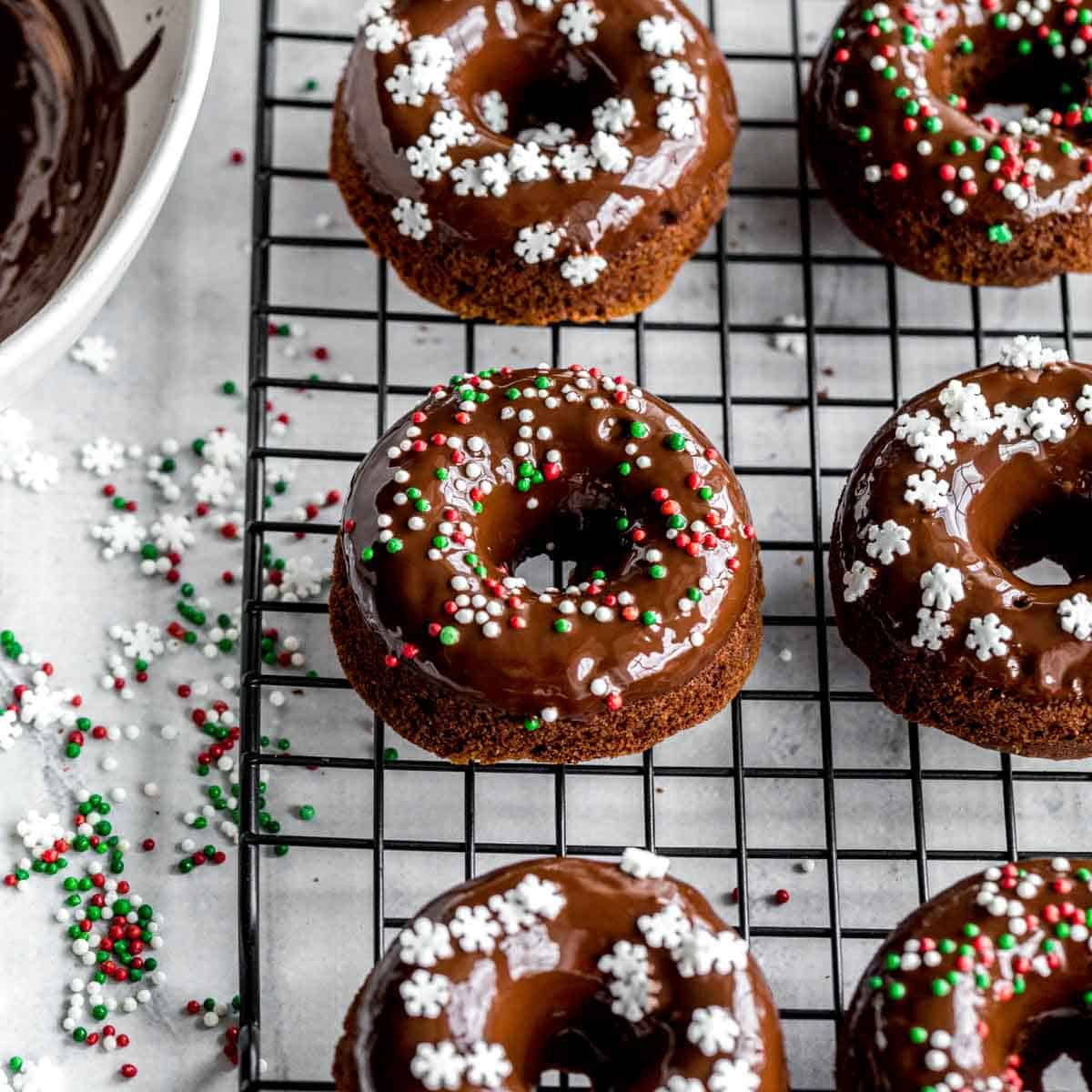 Overhead of mini gingerbread donuts topped with sprinkles and placed on a black wire rack.