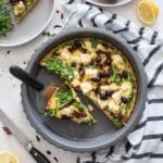 Overhead of Mediterranean quiche in a pie plate with slices removed.