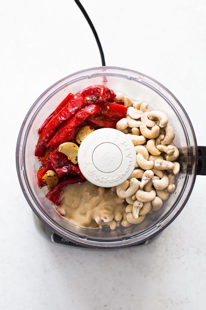 Overhead view of ingredients to make cashew red pepper dip in a food processor.