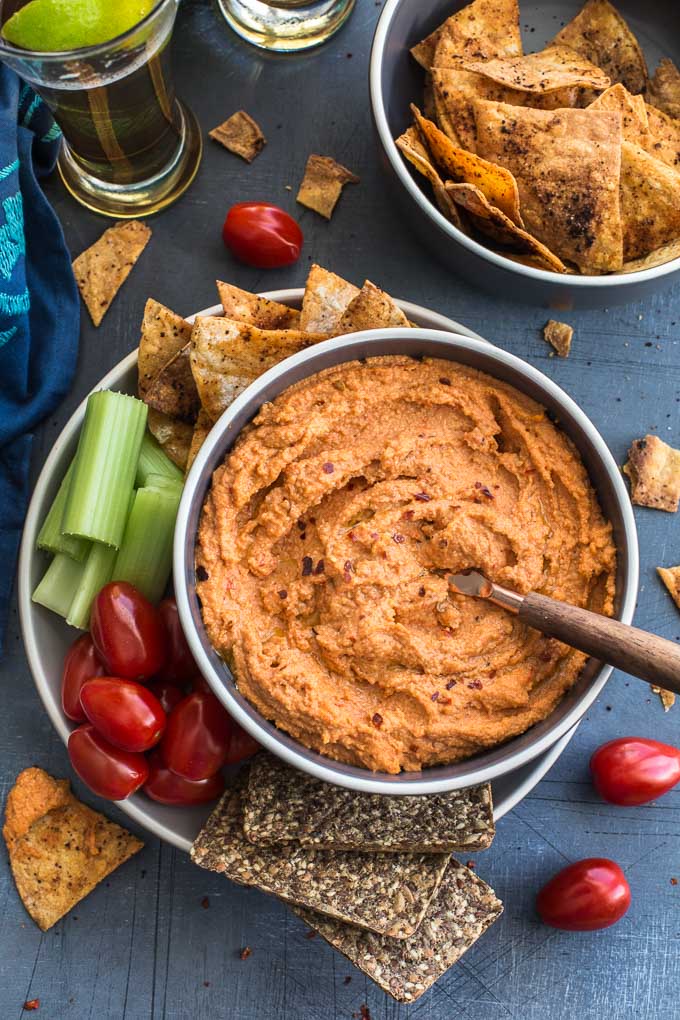 Overhead view of the cashew dip in a bowl surrounded by veggies, chips and beer.