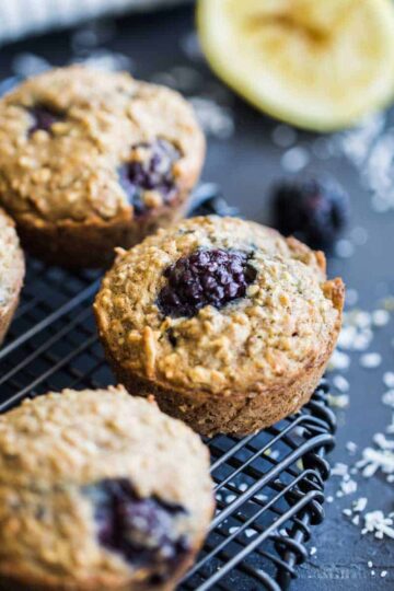 Angled view of blackberry lemon muffins on a round wire rack.