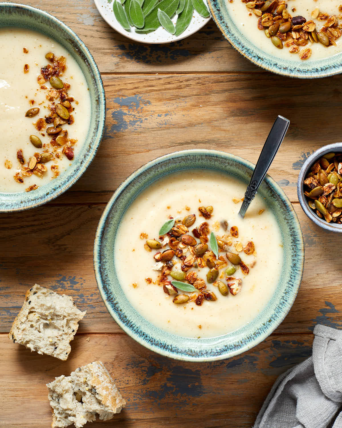 Parsnip and pear soup in green bowls with savoury granola on top.