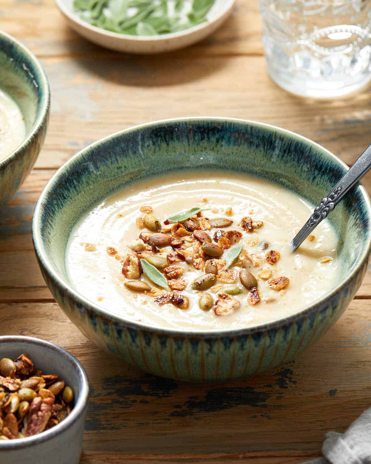 Side view of parsnip soup in a green bowl and topped with granola.