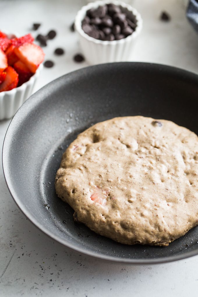Up-close view of a Strawberry Chocolate Chip Buckwheat Pancake cooking in a skillet.