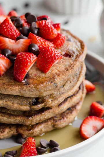 Stack of strawberry chocolate chip buckwheat pancakes on a plate.