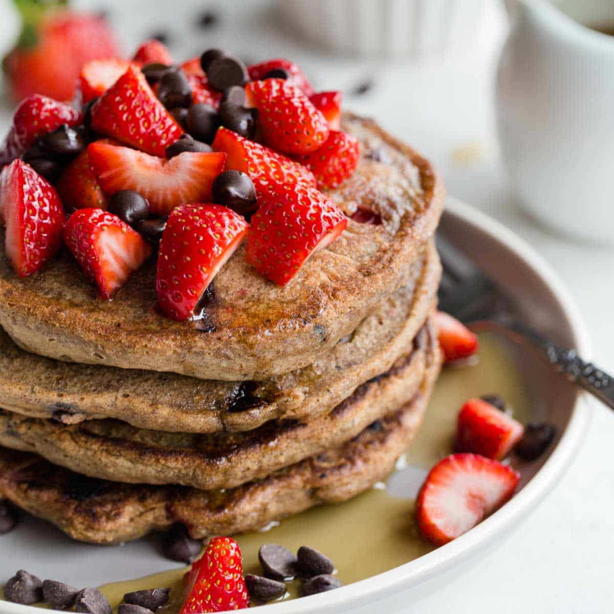 Stack of strawberry chocolate chip buckwheat pancakes on a plate.