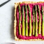 Overhead of beet hummus tart topped with roasted asparagus.