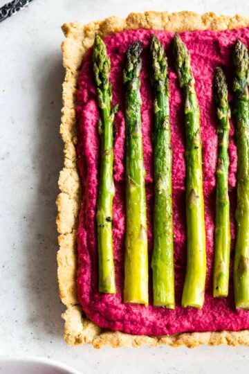 Overhead of beet hummus tart topped with roasted asparagus.