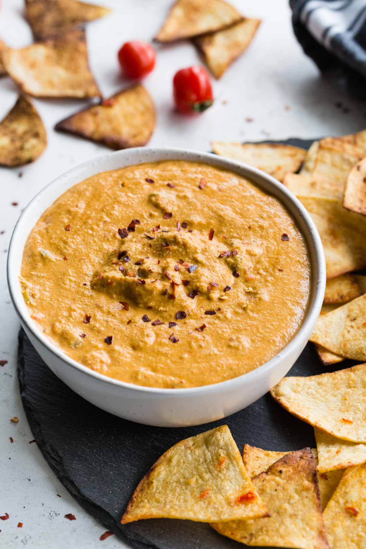 Close up of cashew queso in a white bowl and topped with crushed red pepper flakes.