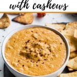 Pinterest image of cashew queso in a white bowl with chips on the side.