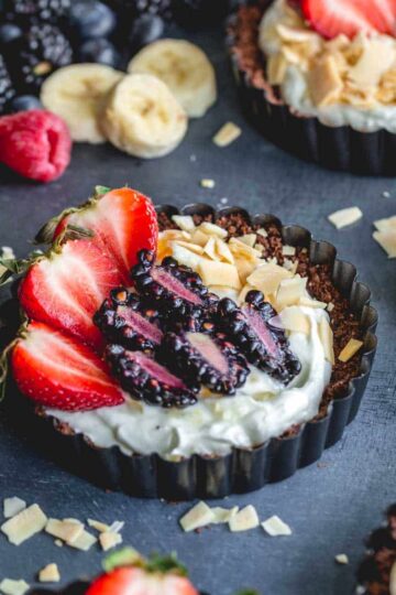 Side view of mini chocolate tarts filled with greek yogurt and topped with berries.