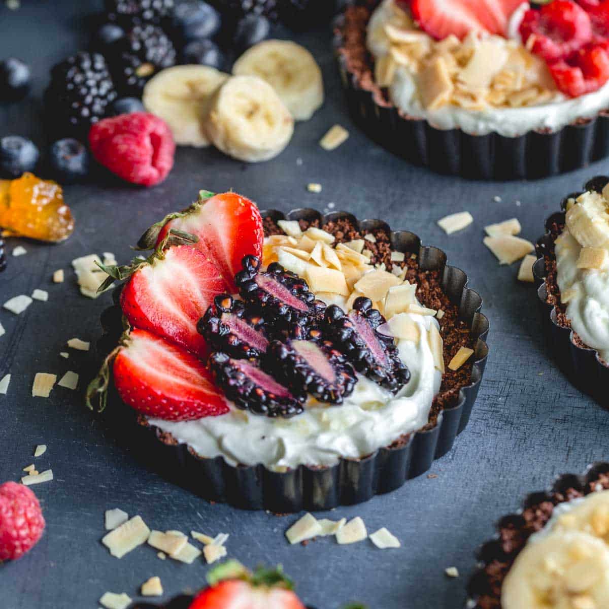 Side view of mini chocolate tarts filled with greek yogurt and topped with berries.