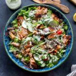 Overhead of salmon pasta salad served in a large blue bowl.