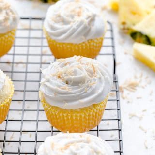 Pineapple coconut cupcakes arranged on a wire rack.