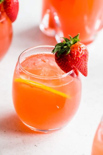 Side view of a glass of rhubarb gin fizz with a strawberry on the rim.