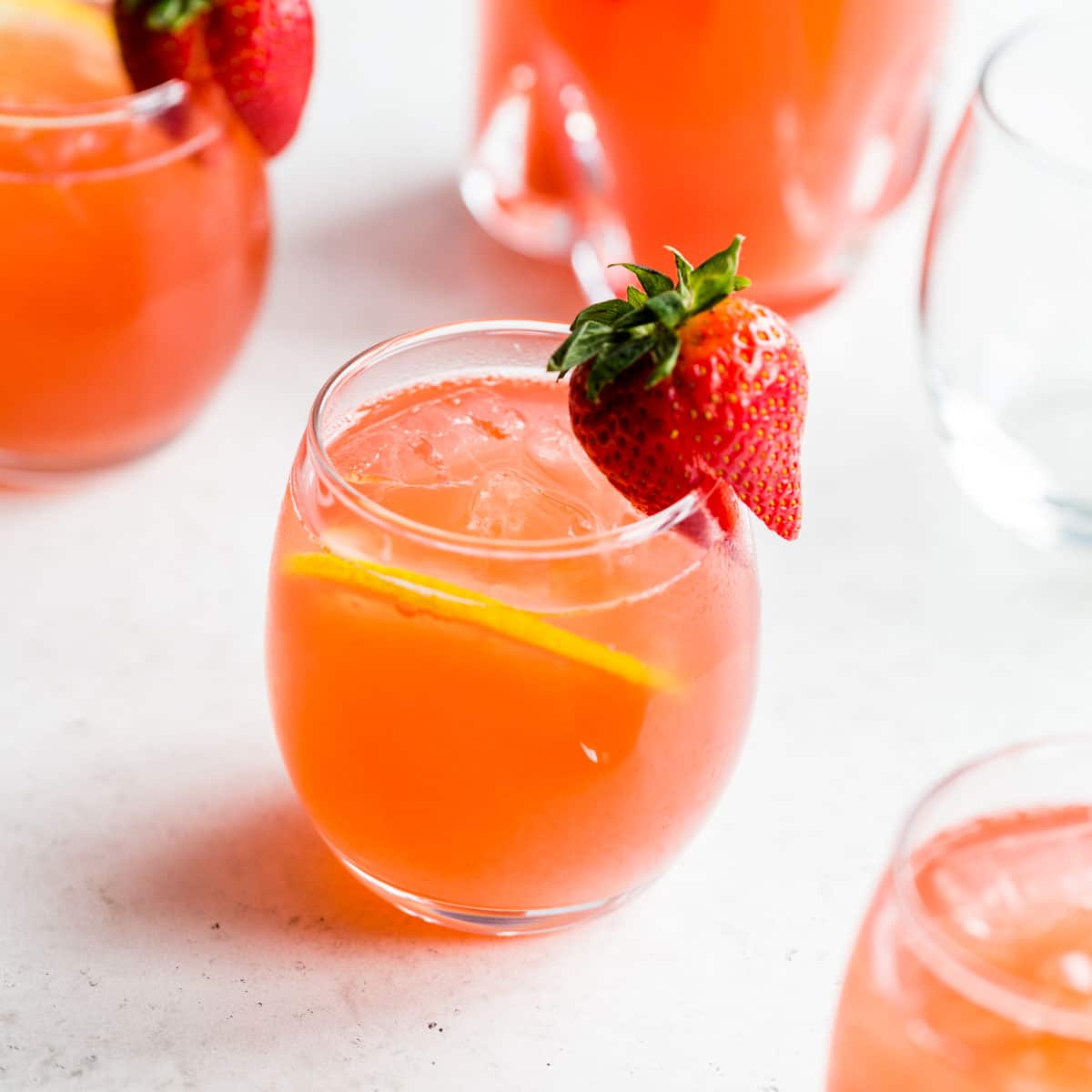 Side view of a glass of rhubarb gin fizz with a strawberry on the rim.