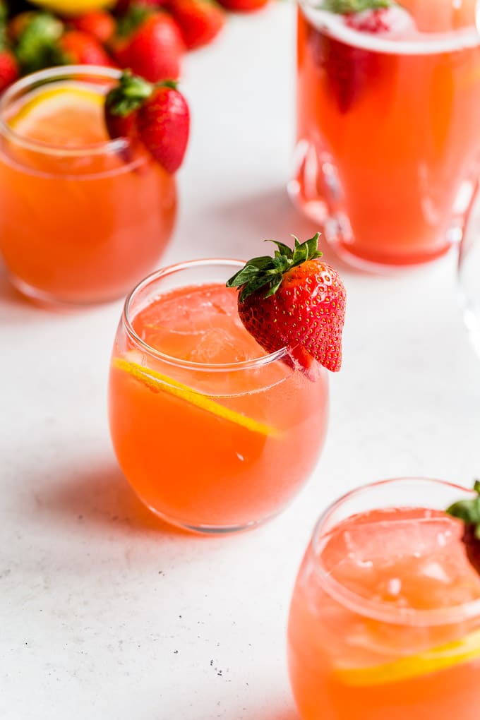 Glasses of strawberry rhubarb gin fizz arranged on a light coloured surface.