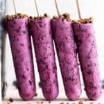 Side view of blueberry goat cheese bars standing up against a tall glass jar.