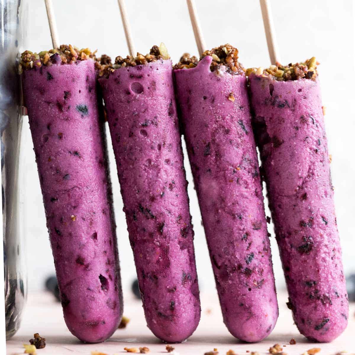 Side view of blueberry goat cheese bars standing up against a tall glass jar.