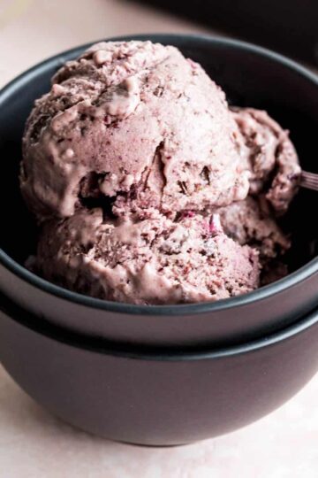Scoops of cherry chip nice cream in a black bowl with a spoon.