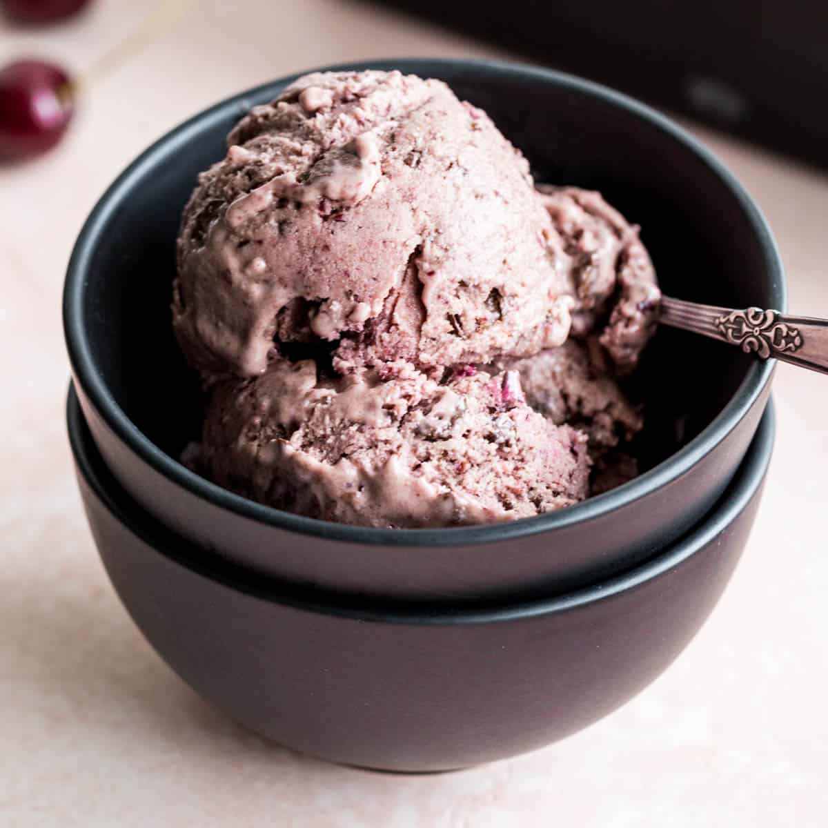 Scoops of cherry chip nice cream in a black bowl with a spoon.